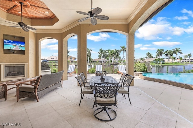 view of patio featuring exterior fireplace, ceiling fan, and a water view