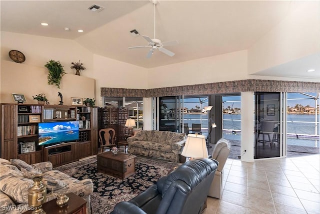 tiled living room with ceiling fan, vaulted ceiling, and a water view