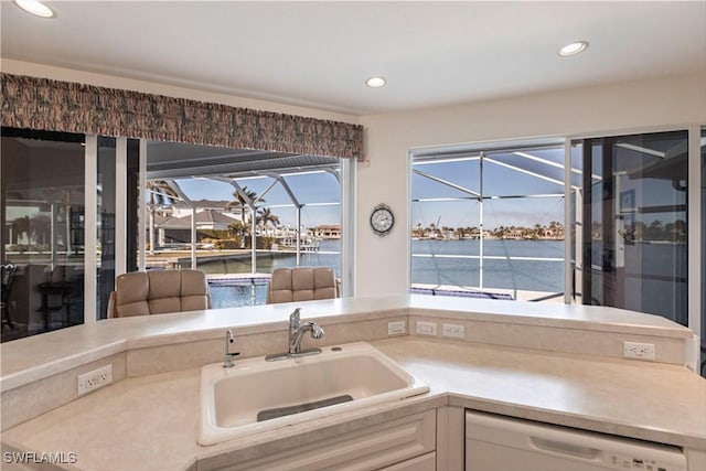 kitchen with white dishwasher, a water view, and sink