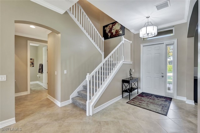 tiled foyer with ornamental molding and a notable chandelier