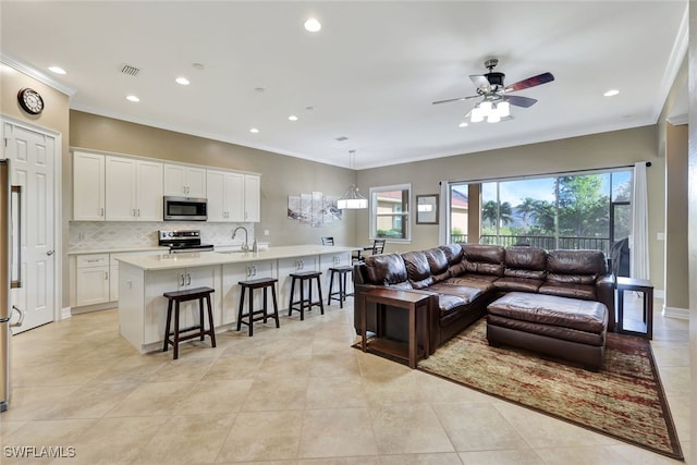 tiled living room with ceiling fan, sink, and ornamental molding