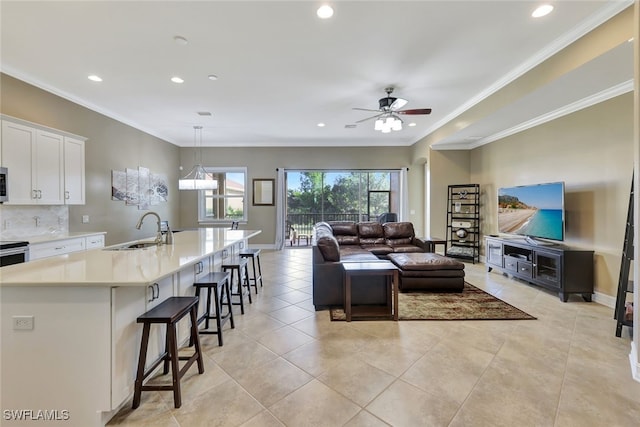 living room with ceiling fan, sink, light tile patterned floors, and ornamental molding