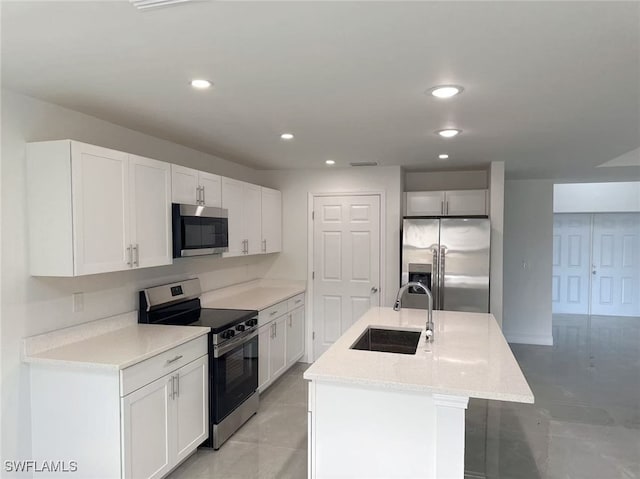 kitchen with sink, white cabinets, light stone countertops, a center island with sink, and appliances with stainless steel finishes