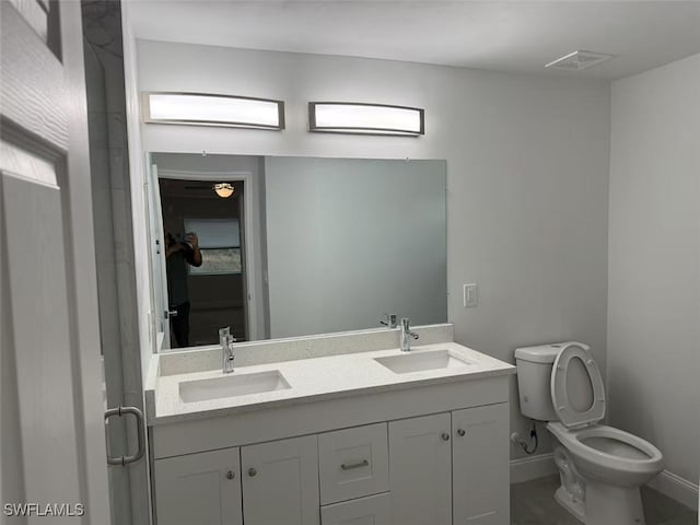 bathroom featuring toilet, a shower with shower door, and vanity