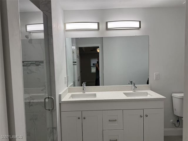 bathroom featuring ceiling fan, vanity, a shower with shower door, and toilet