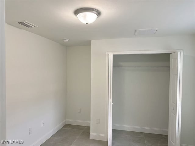 unfurnished bedroom with tile patterned flooring and a closet