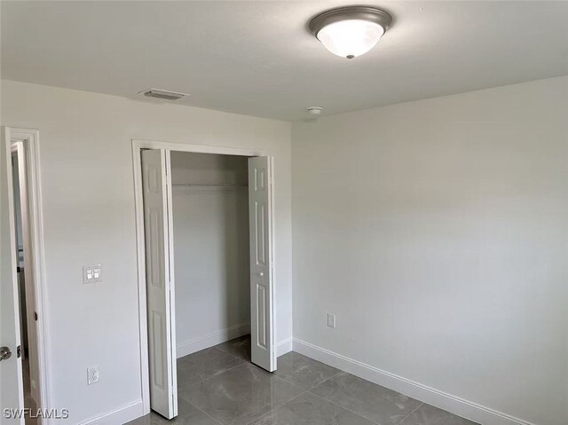 3708 15th St SW, Lehigh Acres, FL 33976 - unfurnished bedroom featuring a closet, baseboards, and dark tile patterned floors