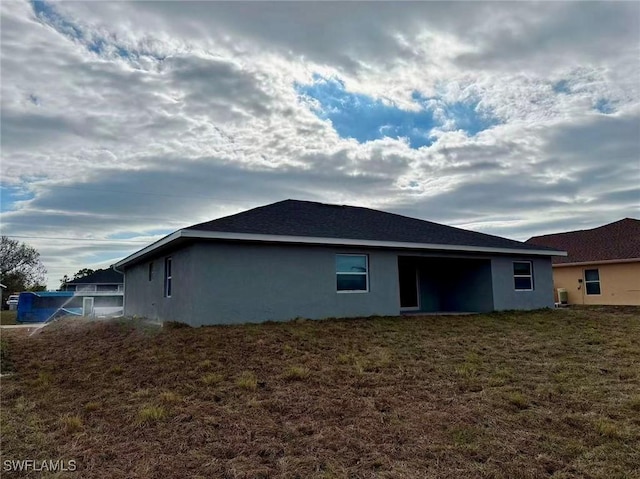 back of property featuring central AC unit and a lawn