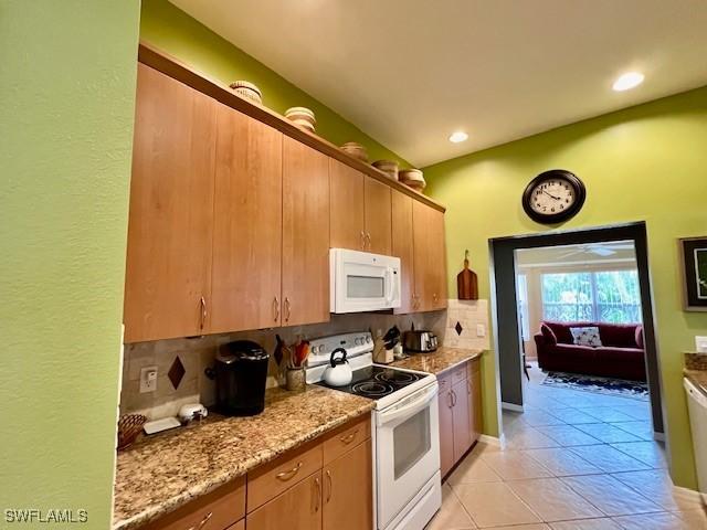 kitchen with white appliances, light stone countertops, light tile patterned flooring, and tasteful backsplash