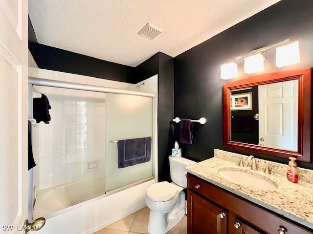 full bathroom with tile patterned flooring, toilet, enclosed tub / shower combo, vanity, and a textured ceiling