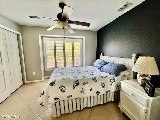 bedroom featuring light tile patterned flooring, ceiling fan, and a closet