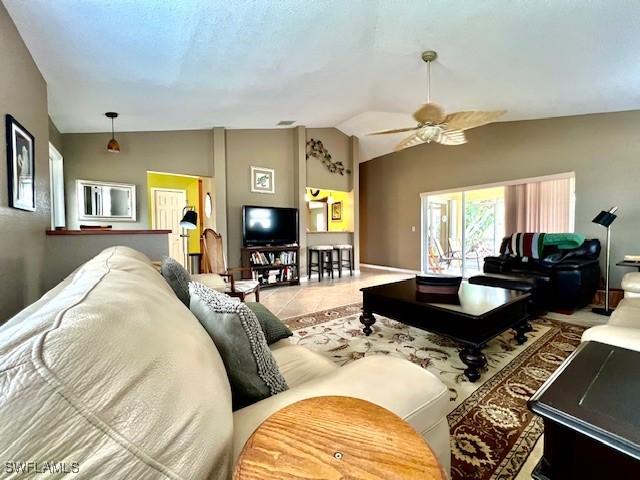 living room featuring tile patterned floors, ceiling fan, and vaulted ceiling