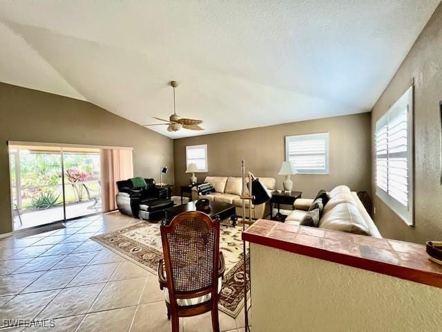 tiled living room featuring vaulted ceiling, ceiling fan, and plenty of natural light