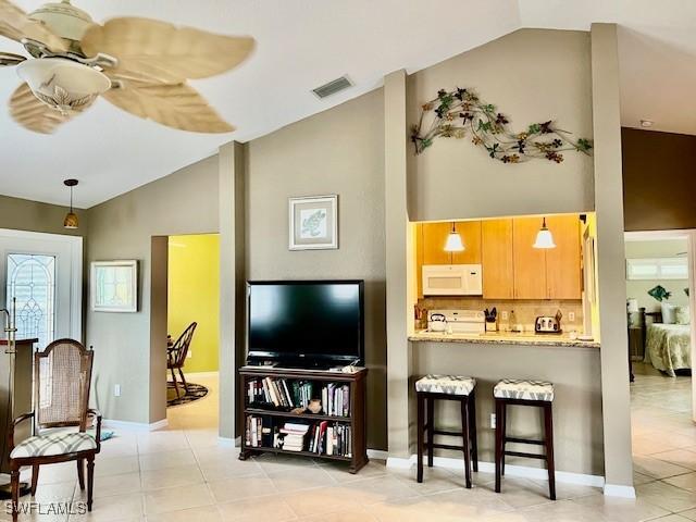 tiled living room featuring ceiling fan and vaulted ceiling