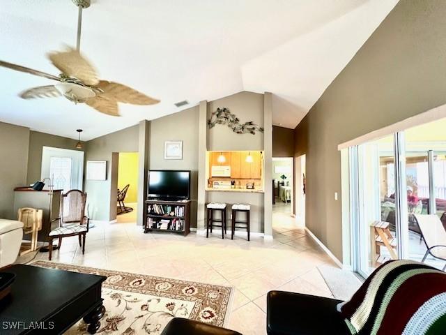 living room featuring ceiling fan, lofted ceiling, and light tile patterned floors