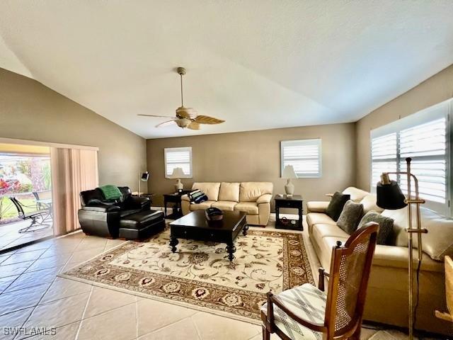 tiled living room featuring lofted ceiling, ceiling fan, and plenty of natural light