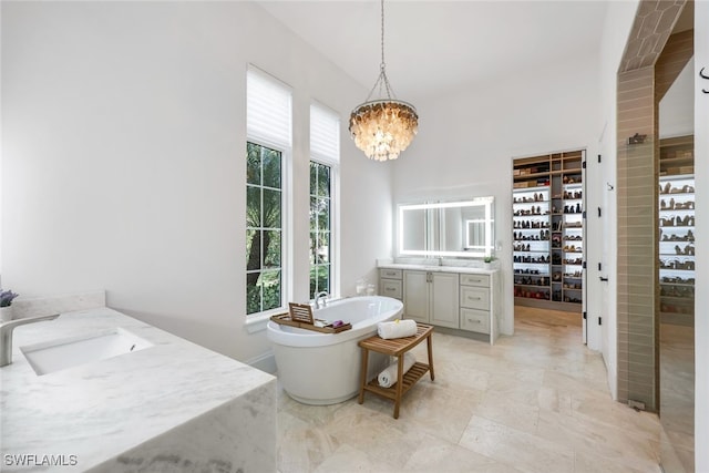 bathroom featuring an inviting chandelier, a bathing tub, and vanity