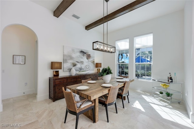 dining area with beamed ceiling and an inviting chandelier