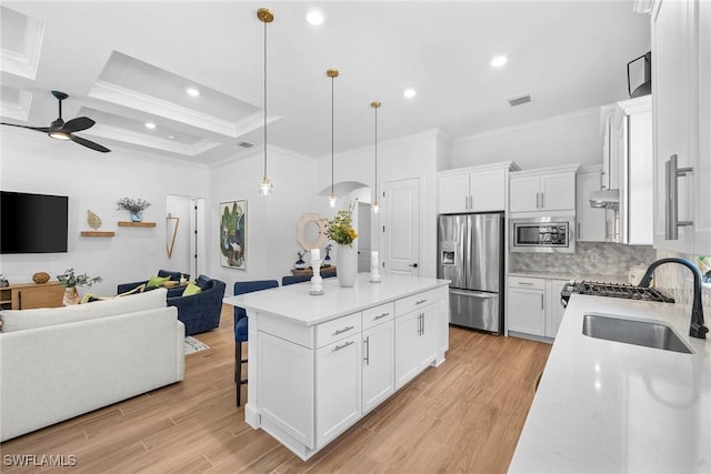 kitchen featuring stainless steel appliances, sink, decorative light fixtures, white cabinetry, and a center island