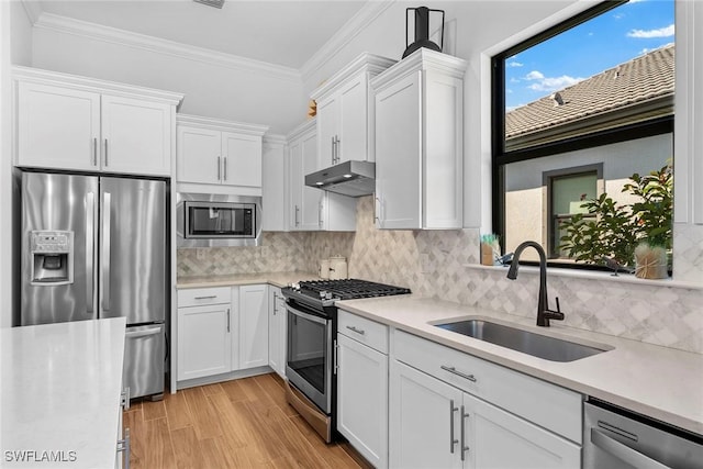 kitchen with stainless steel appliances, sink, white cabinets, ornamental molding, and decorative backsplash