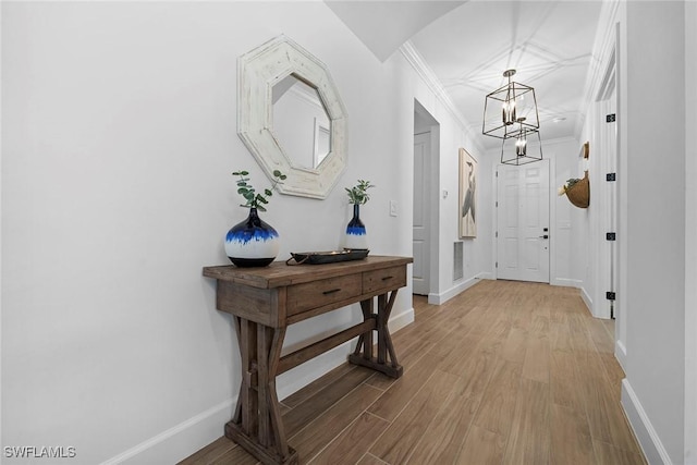 interior space with an inviting chandelier, ornamental molding, and light wood-type flooring