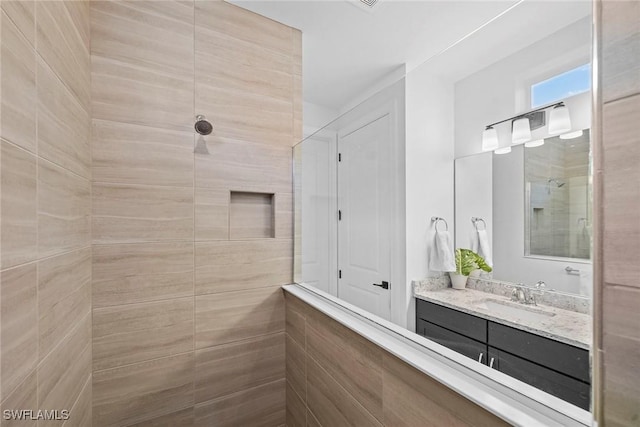 bathroom featuring tiled shower and vanity