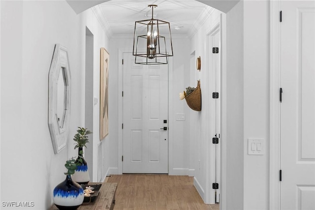 doorway to outside with crown molding, light hardwood / wood-style floors, and a notable chandelier