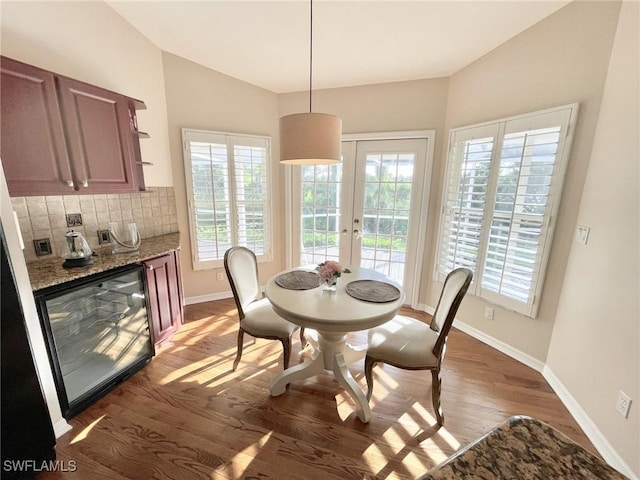 dining space with vaulted ceiling, dark hardwood / wood-style floors, wine cooler, and french doors