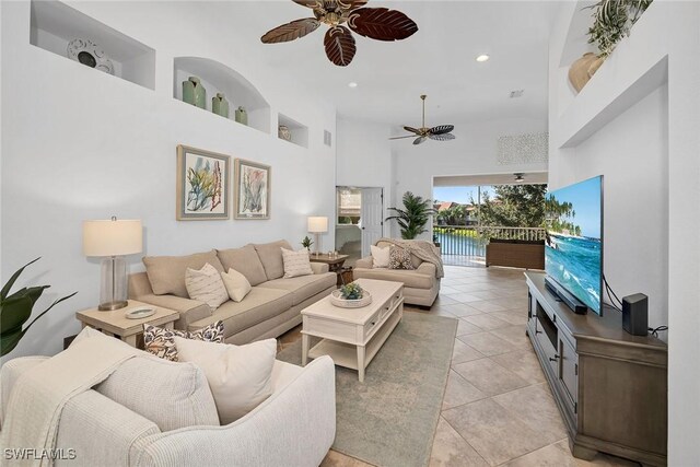 living room with a high ceiling, ceiling fan, and light tile patterned floors