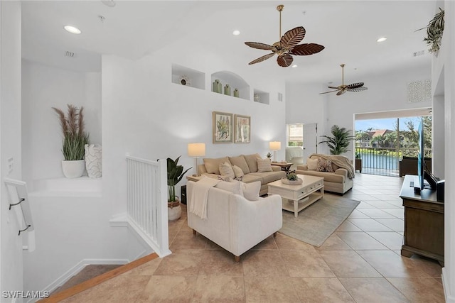 tiled living room featuring ceiling fan and a towering ceiling