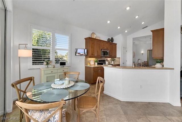 kitchen with stainless steel appliances, kitchen peninsula, lofted ceiling, sink, and backsplash