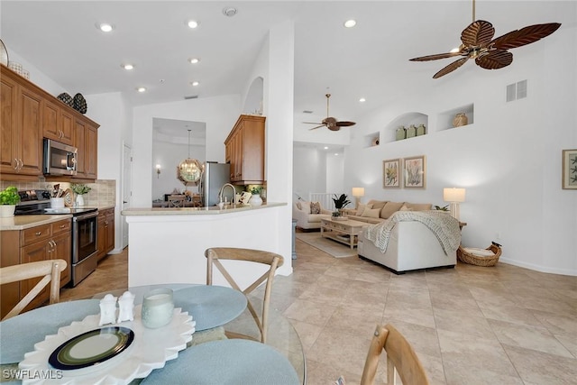 interior space featuring kitchen peninsula, decorative light fixtures, stainless steel appliances, a kitchen bar, and decorative backsplash