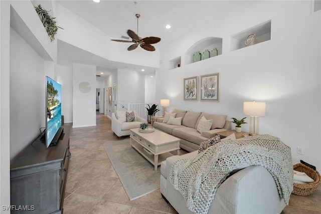 living room featuring a towering ceiling, light tile patterned flooring, and ceiling fan