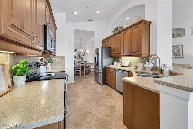 kitchen featuring stainless steel appliances, light stone counters, sink, an inviting chandelier, and lofted ceiling