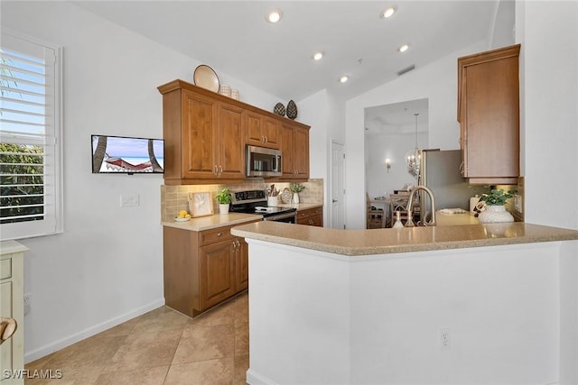 kitchen with lofted ceiling, stainless steel appliances, kitchen peninsula, and sink