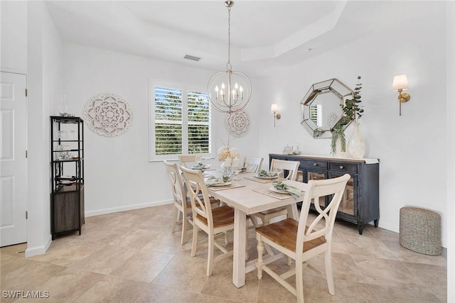 dining room with a raised ceiling and a chandelier