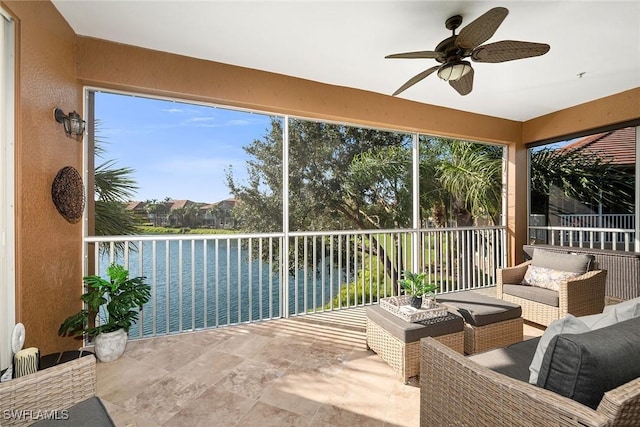 sunroom featuring ceiling fan and a water view