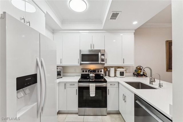 kitchen with appliances with stainless steel finishes, white cabinetry, sink, light tile patterned floors, and crown molding