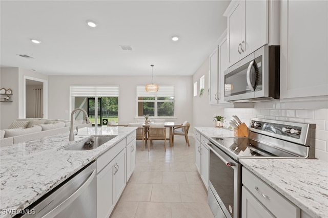 kitchen featuring sink, hanging light fixtures, light tile patterned floors, appliances with stainless steel finishes, and white cabinets