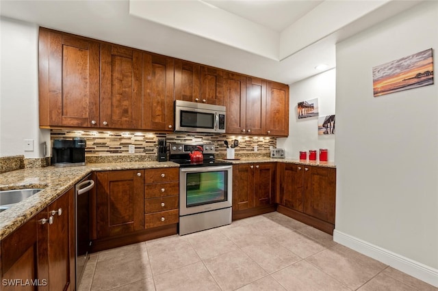 kitchen featuring tasteful backsplash, appliances with stainless steel finishes, light tile patterned floors, and light stone counters