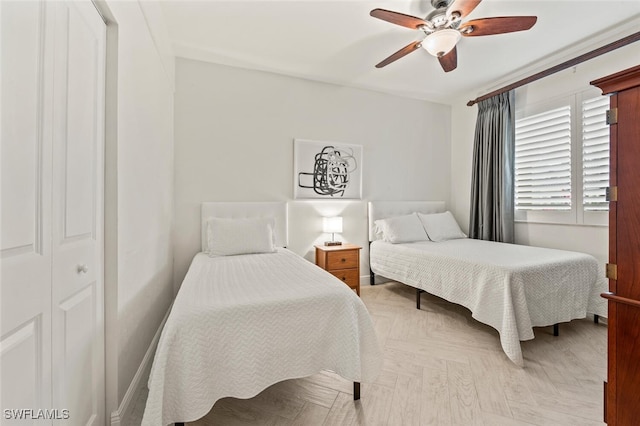 bedroom with light parquet floors, ceiling fan, and a closet