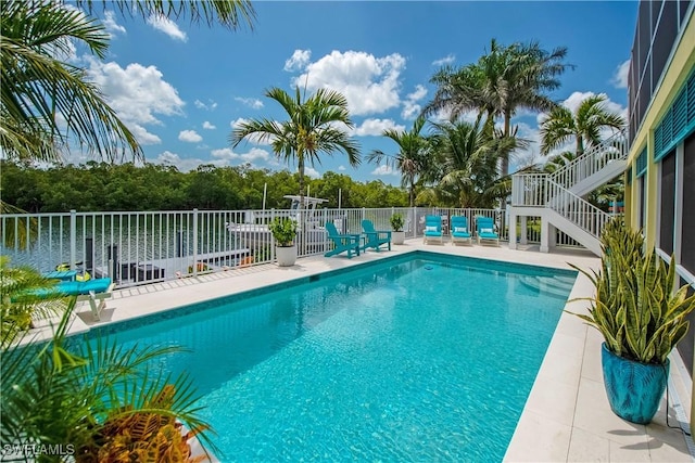 view of pool with a water view and a patio