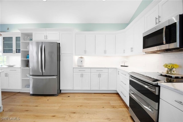 kitchen featuring light wood-type flooring, stainless steel appliances, decorative backsplash, and white cabinets