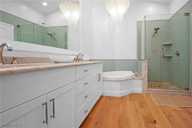 bathroom with vanity, wood-type flooring, a notable chandelier, and plus walk in shower