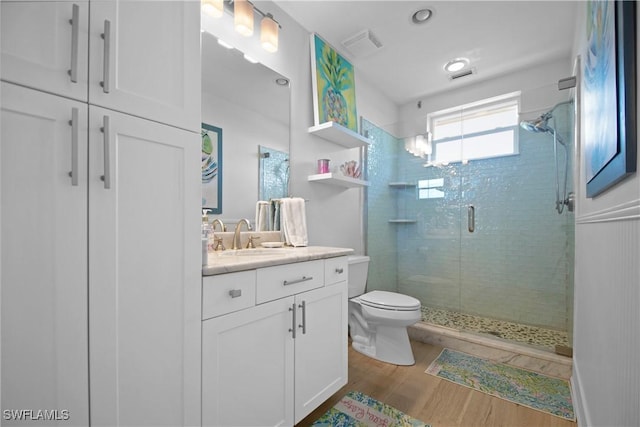 bathroom with toilet, a shower with door, hardwood / wood-style floors, and vanity