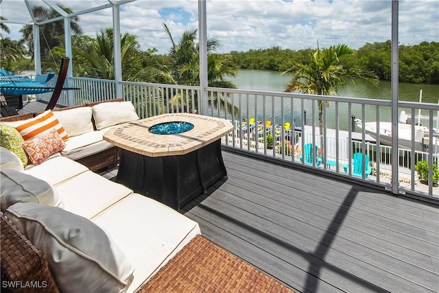 wooden deck featuring a water view and an outdoor living space with a fire pit