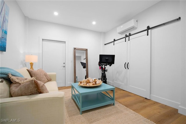 living room featuring a barn door, hardwood / wood-style flooring, and a wall mounted air conditioner