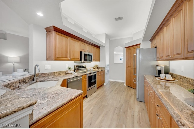 kitchen with sink, light hardwood / wood-style flooring, light stone countertops, crown molding, and appliances with stainless steel finishes