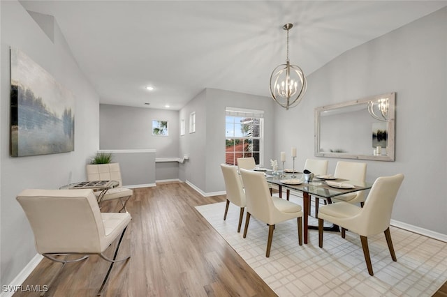 dining space featuring an inviting chandelier, vaulted ceiling, and light hardwood / wood-style flooring