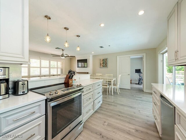 kitchen featuring appliances with stainless steel finishes, light wood-type flooring, ceiling fan, pendant lighting, and white cabinetry